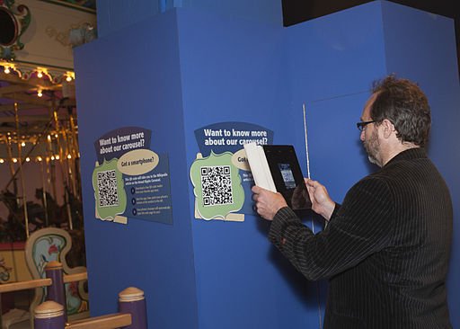 Photo. Jimmy Wales scans the QRpedia code for the Broad Ripple Park Carousel in The Children’s Museum of Indianapolis.