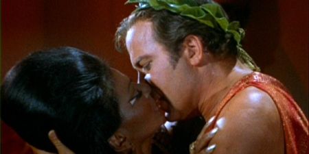 Uhura, a black lady, is kissing Kirk, a white man.