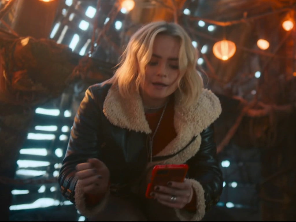 Ruby in the goblin's ship holding a phone.